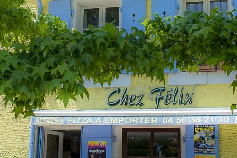 Chez Félix et sa façade jaune sous les arbres de la place centrale